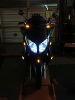 2008 Yamaha Zuma - A dark motorcycle is viewed from the front, its headlights and turn signals illuminated.