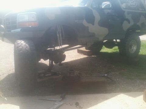 1995 Ford Bronco - Ford Bronco undergoing maintenance, showing lifted suspension and front wheel assembly.