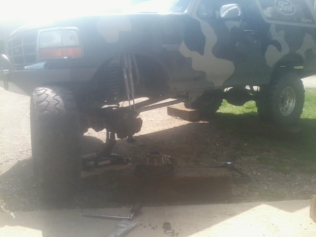 1995 Ford Bronco with camouflage paint, lifted suspension, and front wheel removed for service