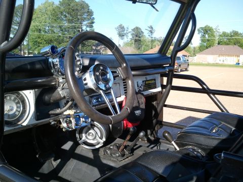 1967 Ford Mustang - Interior of an open-top early Ford Bronco with a black roll cage, showing a Grant three-spoke steering wheel, dash-mounted tach and auxilia…