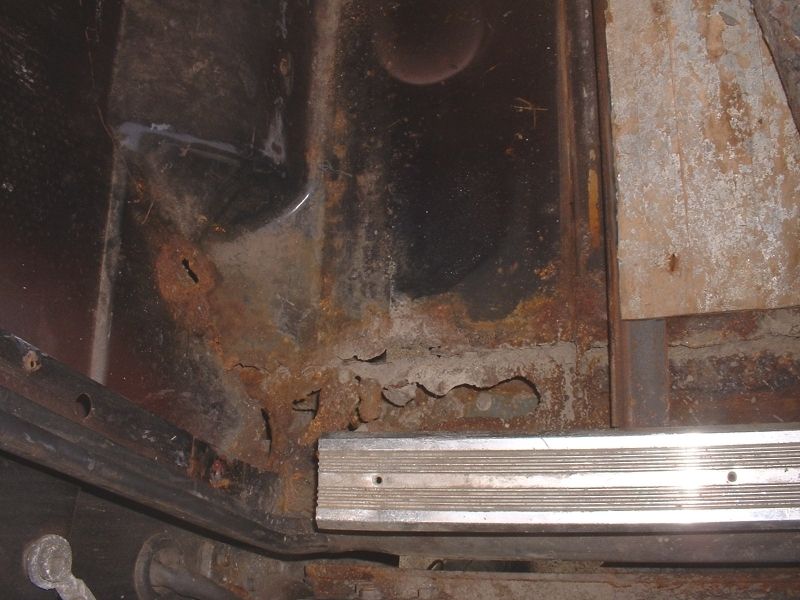 Rusted-through floor pan and rocker area under a truck door sill