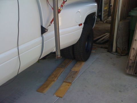 1997 Dodge 3500 - A white dually pickup truck is positioned on wooden ramps in what appears to be a garage or workshop.