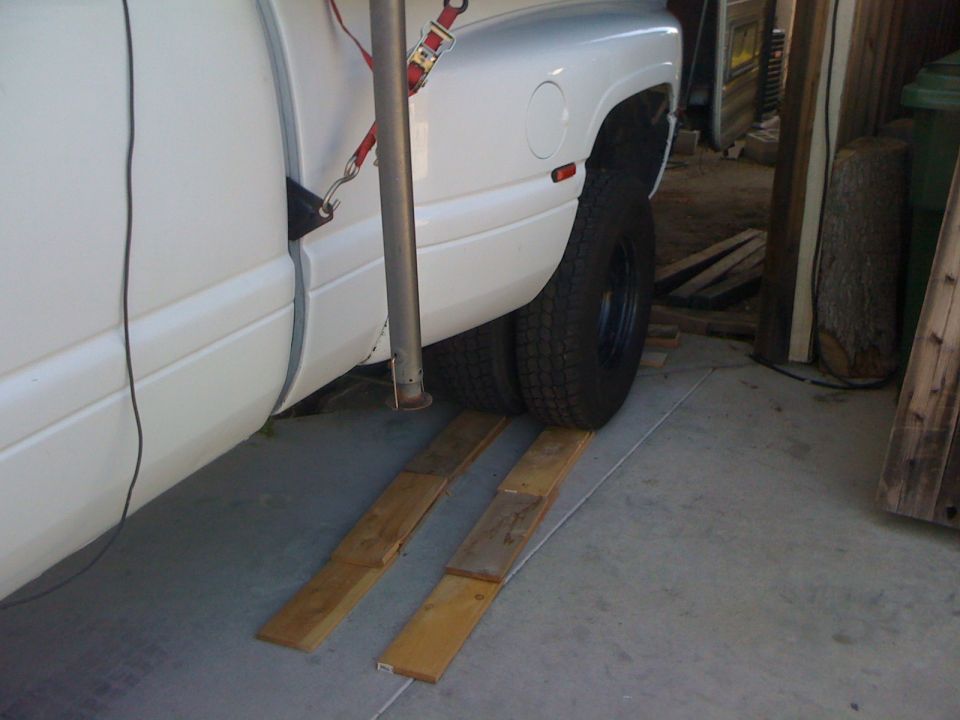 White dually pickup truck on wooden ramps inside a garage