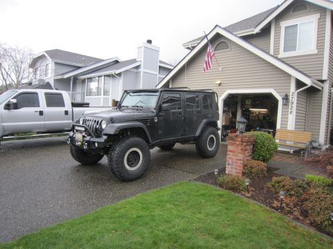 2008 Jeep Wrangler - A black 2008 Jeep Wrangler is parked in a driveway next to a silver pickup truck.