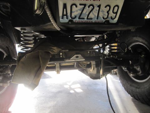1974 Ford Bronco - The underside of a vehicle is visible, including its suspension components and a license plate.