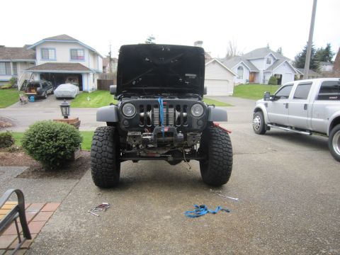 2008 Jeep Wrangler - A Jeep Wrangler is parked in a driveway with its hood open and a winch mounted on the front bumper.