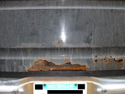 1986 Ford Bronco - Rust damage on the rear panel of a 1986 Ford Bronco, with a Michigan license plate.
