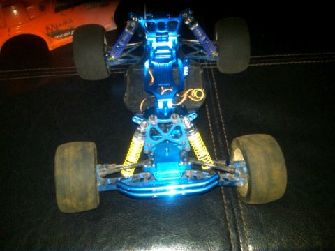 1986 Ford Bronco - The underside of a blue remote control car chassis is shown, with another RC car body in the background.