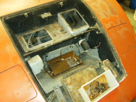 2000 Ford E350 - The engine bay of an orange vehicle shows signs of disuse and rust, with various components visible.