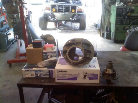 1988 Ford Bronco - Yukon differential parts laid out on a workbench with a modified vehicle in the background.