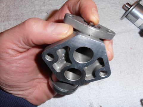 1990 Ford Bronco - A metal automotive part is held in a hand, with another similar part visible in the background.