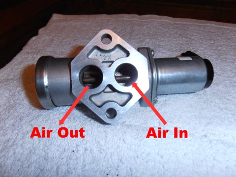 1990 Ford Bronco - Close-up of an idle air control valve, labeled with air intake and output directions.