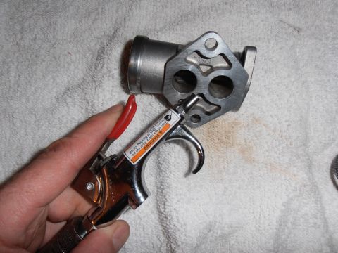 1990 Ford Bronco - A hand is shown holding an air duster tool near a metal throttle body component, resting on a white towel.