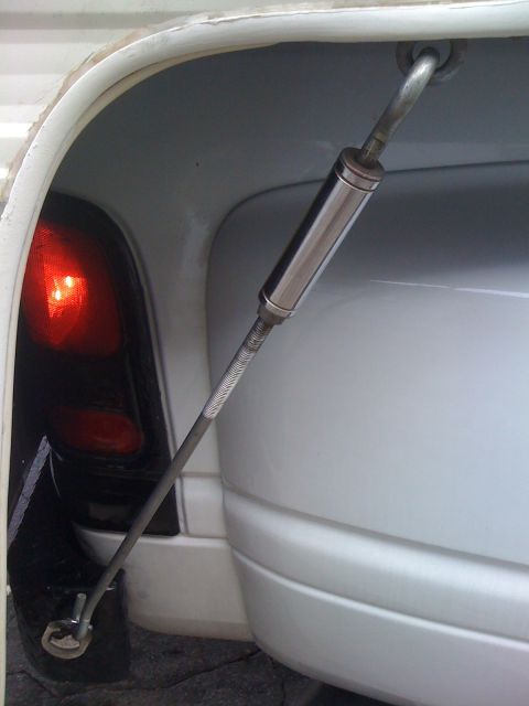 1986 Yugo GV - Close-up of a white car's rear bumper and taillight, showing a metal strap used for securing a component.