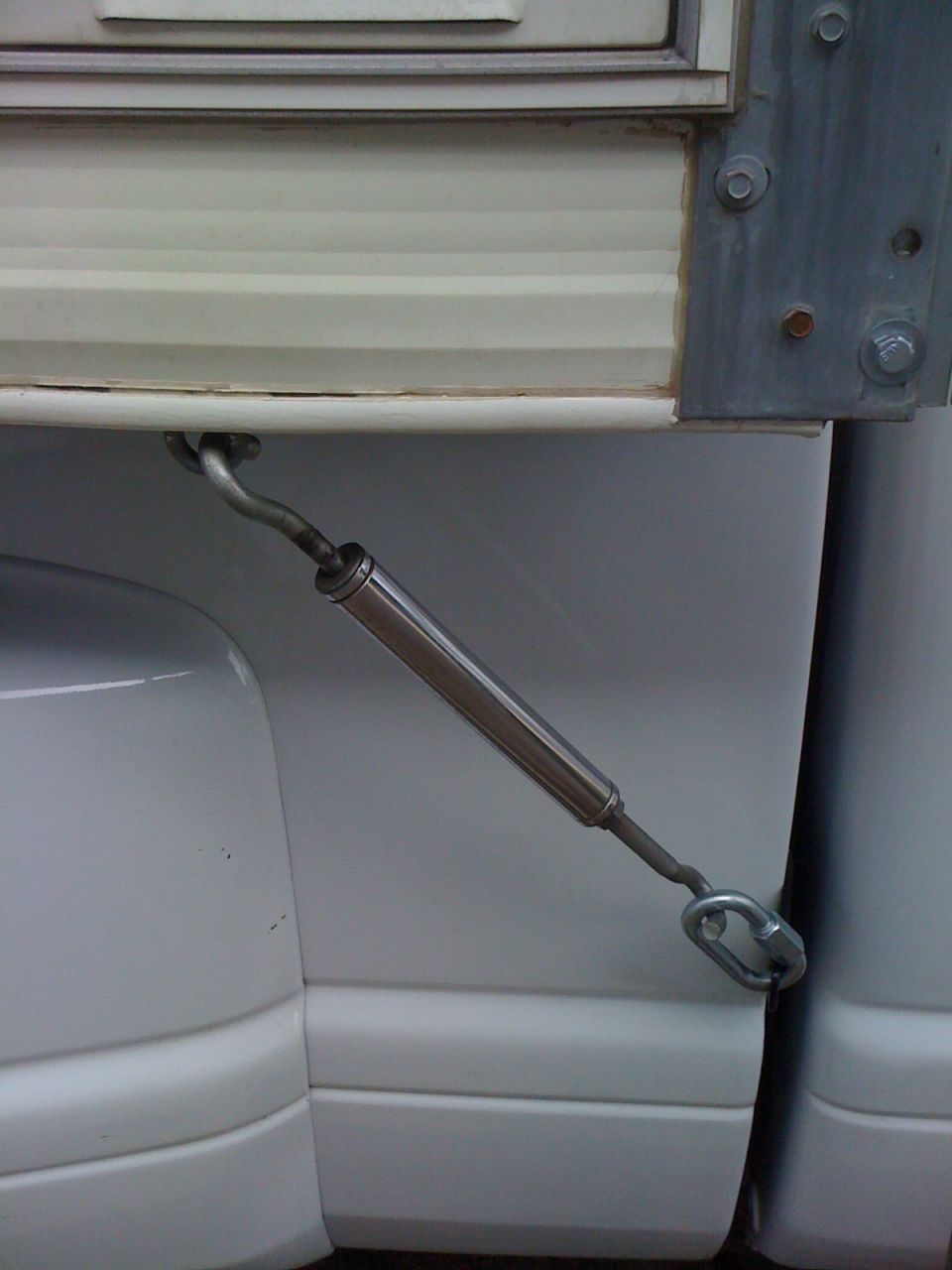 Stainless turnbuckle and quick link securing a camper to a truck bed rail