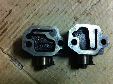 1998 Ford Crown Victoria - Two metal timing chain tensioners are shown, with visible casting marks and part numbers.
