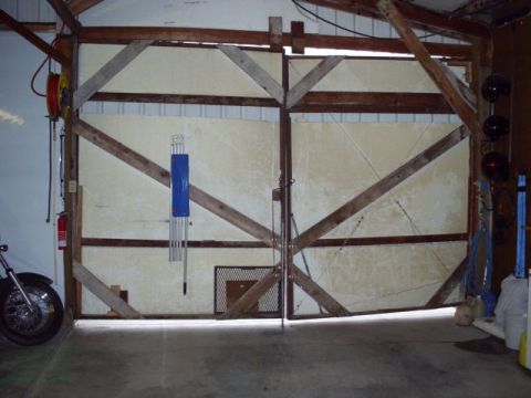 1989 Ford Bronco - A motorcycle is partially visible in a garage with large wooden doors.