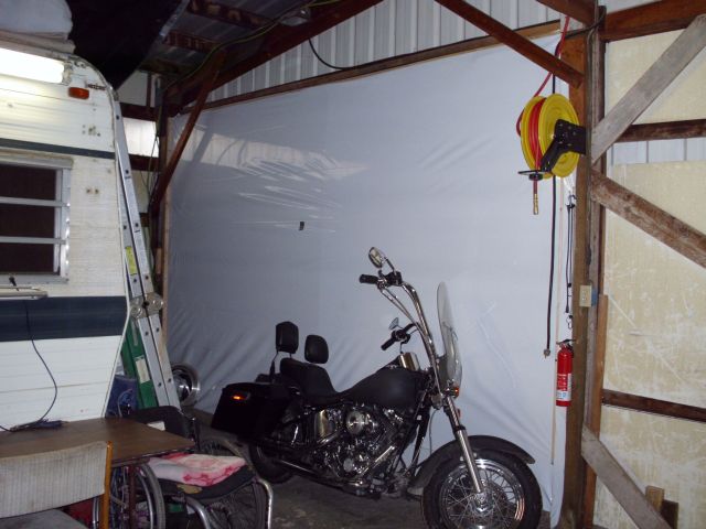 Motorcycle parked inside a garage next to a trailer and a wheelchair