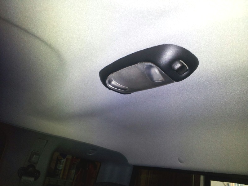 Interior dome light on a gray headliner, with a partial view of the rear cabin area and a Supermotors watermark