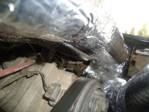 1995 Ford Bronco - Close-up view of insulated pipes and engine components in a vehicle's engine bay.