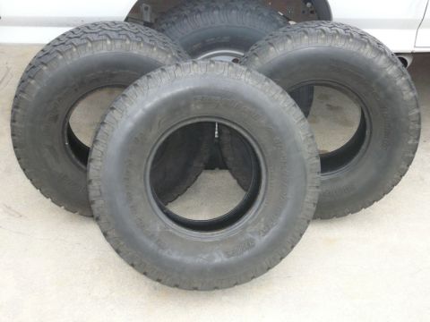 1988 Ford Bronco - Four BFGoodrich All-Terrain T/A tires are visible, with a portion of a white vehicle in the background.