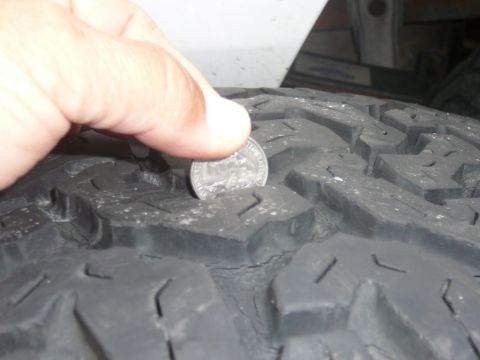 1988 Ford Bronco - Tire tread depth is checked using a quarter, indicating the remaining tread life.