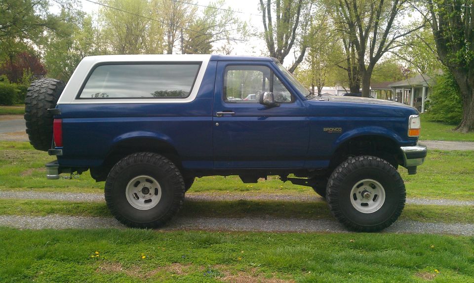Blue 1996 Ford Bronco side view with white top and spare tire