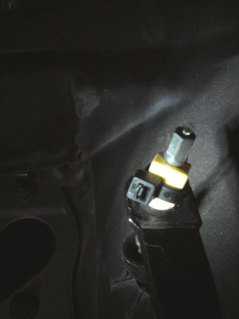 1996 Ford Bronco - Close-up of a vehicle's throttle cable connector, showing a yellow clip and hex nut.