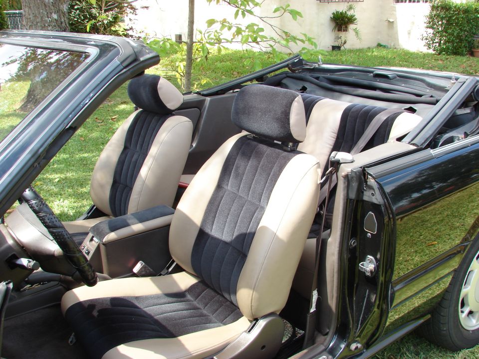 Convertible interior with two-tone black and tan seats, top down, parked on grass