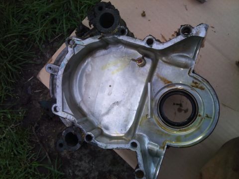 1994 Ford Bronco - An engine timing cover, likely removed for repair or replacement, shows signs of wear and oil residue.