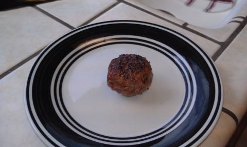 1989 Ford Bronco - A single, cooked meatball rests on a white plate with black and blue stripes.