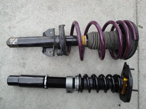 1995 Ford Taurus - Two automotive suspension coilover assemblies are shown side-by-side on a concrete surface.
