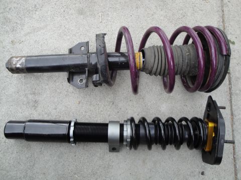 1995 Ford Taurus - A comparison of two different car suspension strut assemblies, one with a purple spring and the other with a black adjustable spring.