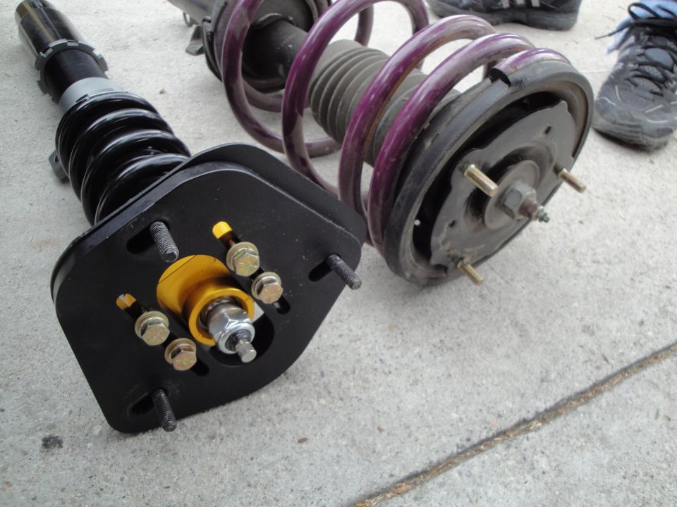 Two coilover suspension assemblies with purple and black springs on concrete