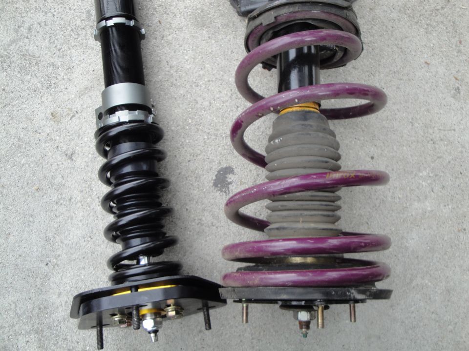 Comparison of two car suspension coilover assemblies, one black and one with purple springs