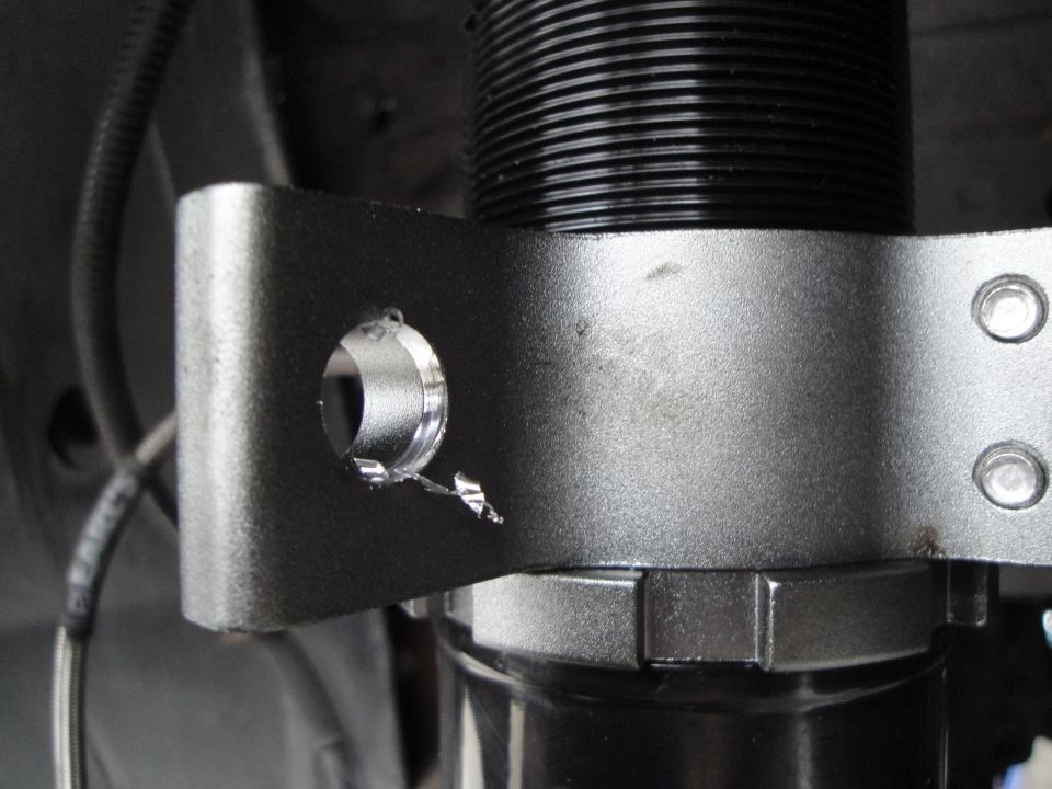 Close-up of a coilover suspension part with a drilled mounting bracket