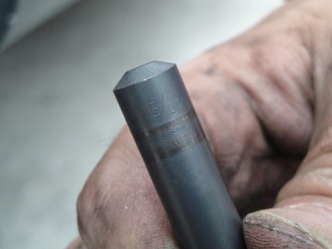 1995 Ford Taurus - A hand holds a metal tool marked with measurements, likely a drill bit or punch.