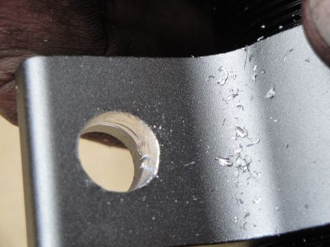 1995 Ford Taurus - Close-up of a metal bracket showing a drilled hole and debris from the drilling process.