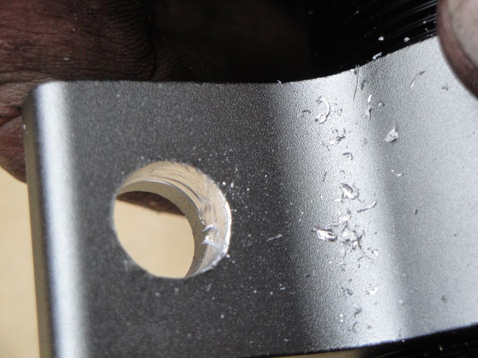 Metal bracket with a freshly drilled hole and metal shavings