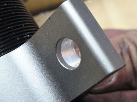 1995 Ford Taurus - A close-up view of a metal bracket attached to a black coilover shock absorber, showing a mounting hole.