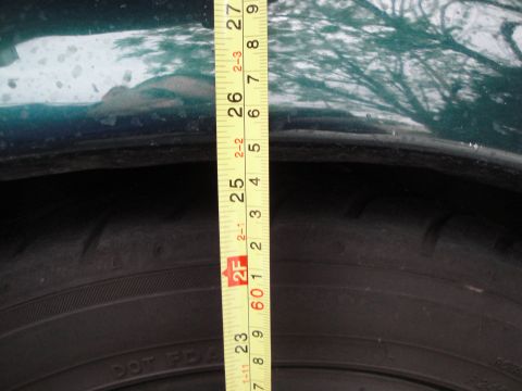 1995 Ford Taurus - A measuring tape is placed between the tire and the fender of a green vehicle.