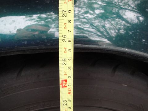 1995 Ford Taurus - Measuring the clearance between the tire and fender on a green vehicle.
