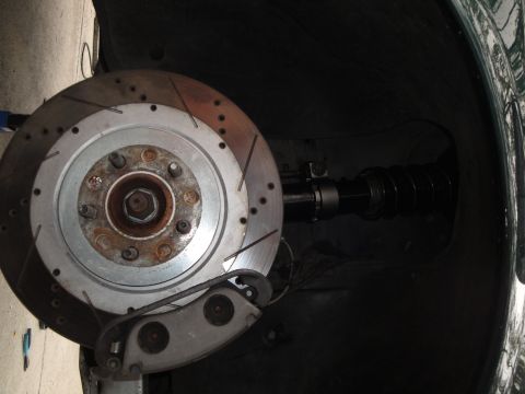 1995 Ford Taurus - A close-up view of a vehicle's front brake rotor and suspension system.