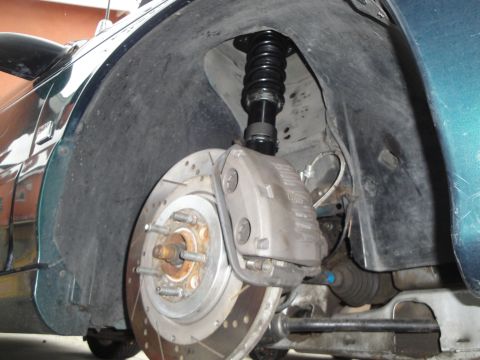 1995 Ford Taurus - Aftermarket coilover suspension installed in the front wheel well of a car.