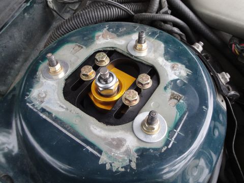 1995 Ford Taurus - Aftermarket adjustable coilover mount installed on a dark green vehicle's strut tower.