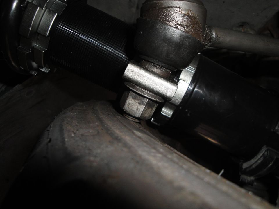 Black coilover suspension part with adjustable collars and a metal bracket