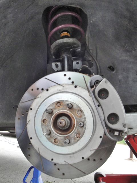 1995 Ford Taurus - Close-up of a vehicle's brake system and suspension components, including a drilled rotor and caliper.