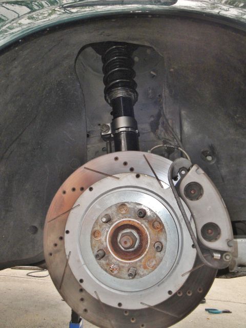 1995 Ford Taurus - Close-up of a front wheel well showing a slotted brake rotor and performance coilover suspension.