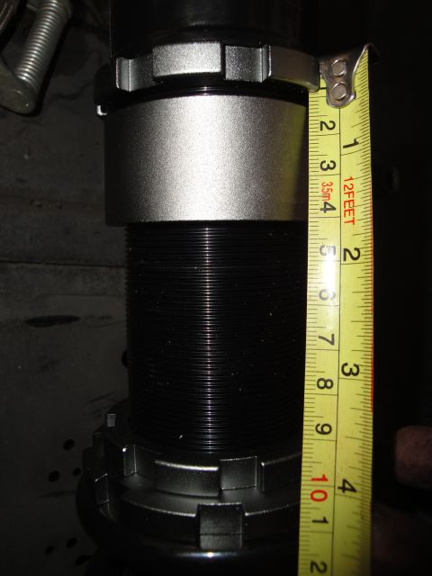 1995 Ford Taurus - A tape measure is used to measure the height of a black coilover suspension component.