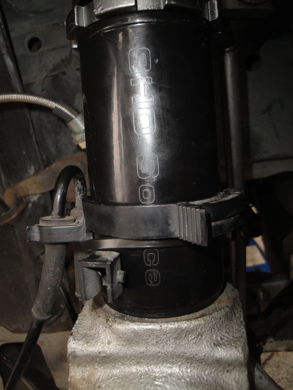 Black coilover shock absorber with 'SHO' and 'CE' markings, attached to suspension components
